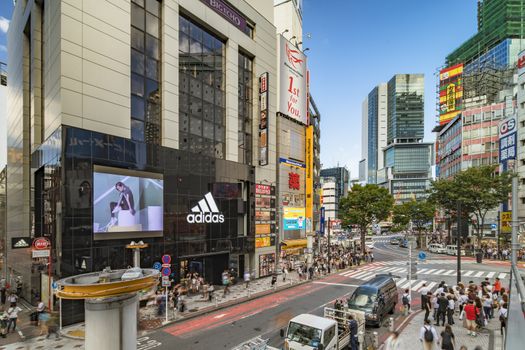 Shibuya Crossing Intersection in front of Shibuya Station on a bright day blue sky.