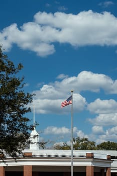 An American flag flying under a clear blue sky in front of a brick pavilion