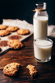 Oatmeal Cookies with Raisins and Glass of Milk for Breakfast. Some Cookies on Parchment Paper with Bottle on Backdrop. Vertical Orientation.