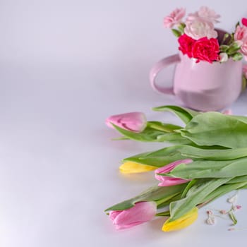 Bouquet of yellow and pink tulips on white background. Valentine's Day and Mother's Day background. Cup with flowers.