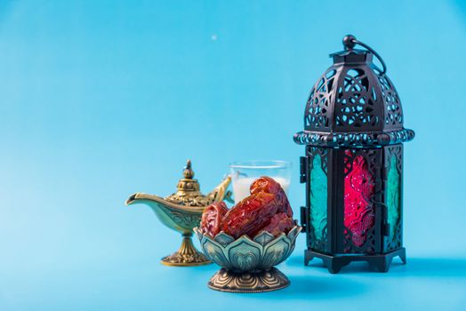 Ramadan Kareem fasting Food Concept, Bronze plate dates, milk, and lantern Aladdin lamp decoration, eid Arabian Muslim religious festival on a blue background with copy space for text