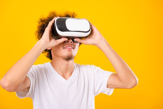 Asian handsome man with curly hair he using virtual reality headset or VR glass isolate on yellow background