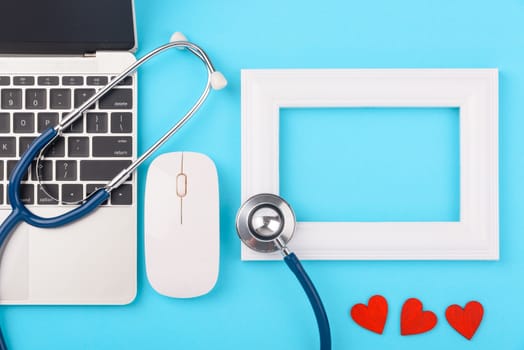 Doctor's Day concept, flat lay top view, stethoscope with laptop computer and photo frame diagnosis of heart disease on blue background with copy space for text