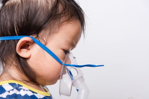 Closeup Asian face, Little baby girl sick her using steam inhaler nebulizer mask inhalation oneself on white background with copy space, health medical care