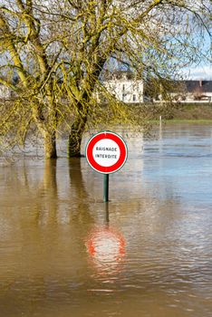 Flooded sign which reads no swimming. Loire River in Amboise, France.