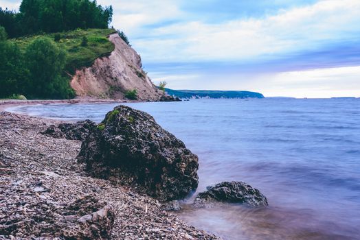 stone on the riverbank and cliff with birch woodland on background