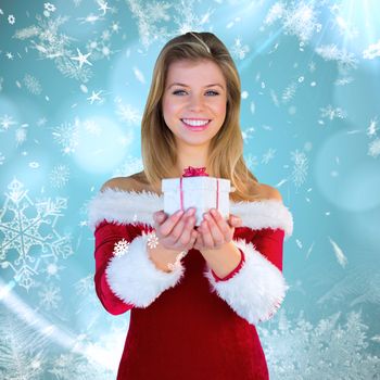 Pretty girl in santa outfit holding gift against blue snow flake pattern design