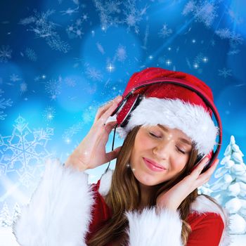 Sexy santa girl listening to music against snowy landscape with fir trees