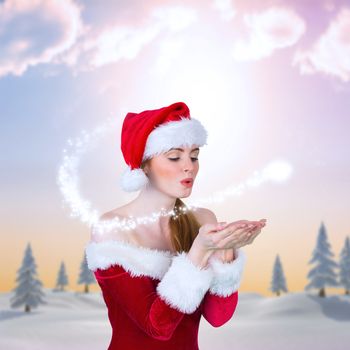 Pretty girl in santa costume holding hand out against snowy landscape with fir trees