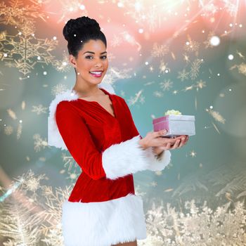 Pretty santa girl holding gift against cream snow flake pattern design