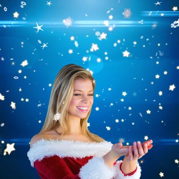 Pretty girl holding hands out in santa outfit against bright star pattern on blue