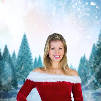 Pretty girl smiling in santa outfit against snowy landscape with fir trees