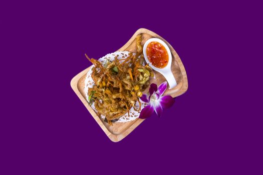 Thai food nicely prepared and displayed on purple background on wooden and white plates with to spicy sauces and shrimp