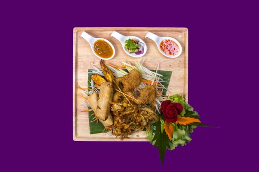 Mixed plate with thai food with purple background and copy space. Plate made out of wood