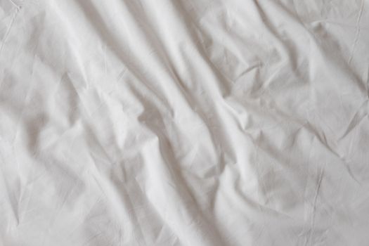 Background of white rumpled sheets. Bed linen with wrinkles in day light. Horizontal. Copy spase. Concept of rest, awakening, sleep. For social media, blog.