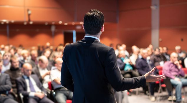 Speaker at Business Conference with Public Presentations. Audience at the conference hall. Entrepreneurship club. Rear view. Panoramic composition. Background blur.