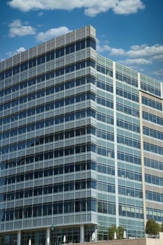 A modern blue steel and glass office building under a clear blue sky