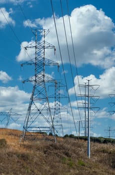 High power lines on towers across a blue sky