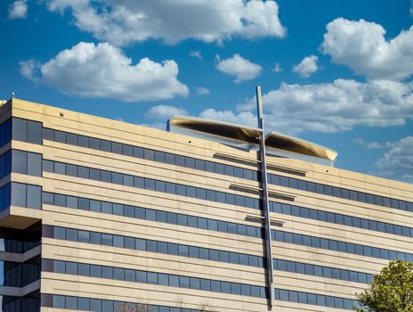 Metal cross shaped architectural detail on a concrete and blue glass office building