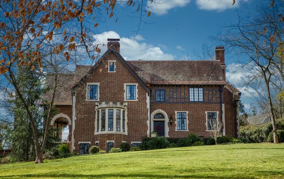 An old brick home with classic stone encased windows on a green grass lawn