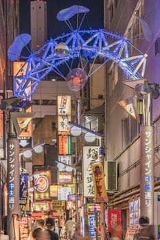Illuminated entrance gate with security camera operating at the Sunshine Central Street connecting the east exit of Ikebukuro station lines with yakitori and sushi restaurants, shops, game center and cinemas leading to the famous otaku's town otome road.