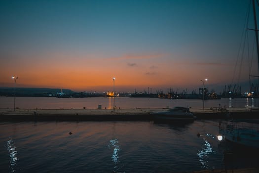 Sunset landscape combined with lights reflecting in the sea and some boats.