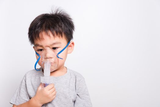 Closeup Asian face, Little children boy sick he using steam inhaler nebulizer mask inhalation oneself on white background, health medical care