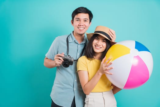 Happy Asian young beautiful woman handsome man couple in summer in holiday travel beach accessories ball and camera isolated on blue background with copy space for text