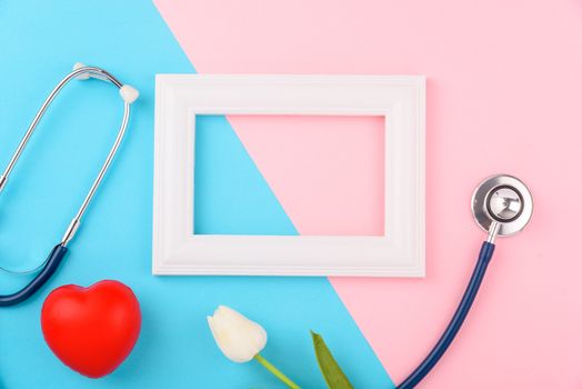 Doctor's Day concept, flat lay top view, stethoscope with photo frame and red heart on pink blue background, diagnosis of heart disease with copy space for text