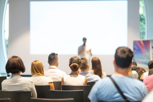 Male speaker giving a talk in conference hall at business event. Audience at the conference hall. Business and Entrepreneurship concept. Focus on unrecognizable people in audience.