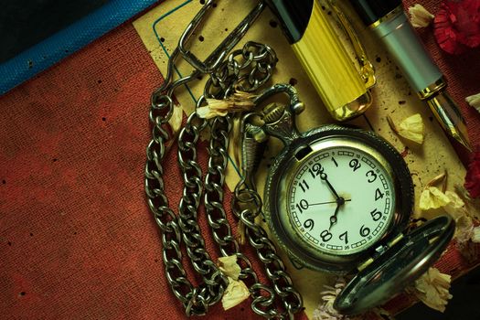 Vintage pocket watch and brass pen on old book. At 8 o’clock in morning. Top view and copy space. Education and vintage style concept.