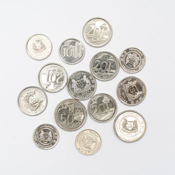 some Singaporean dollar coins on a white surface