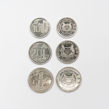 some Singaporean dollar coins on a white surface