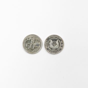 some Singaporean dollar coins on a white surface