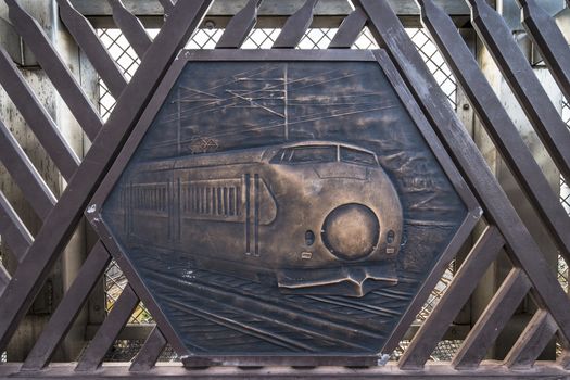 Engraving on metal representing the Super Hitachi train on the Shimogoindenbashi Bridge that reaches the Nippori and Yanaka neighborhoods in the Arakawa district at the north exit of the Nippori Station on the JR Yamanote Line in Tokyo. In the center of the bridge is a balcony called the Train Museum which allows to observe the 2500 trains that pass each day below. The bridge dating back to the 1930s has been renovated several times to adapt to the evolution of traffic and was completed in its current form in 1988.