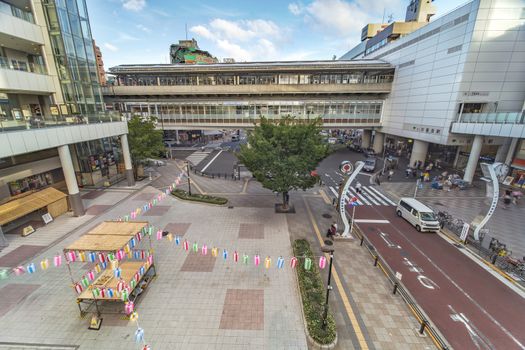 View of the square in front of the Nippori train station decorated for the Obon festival in the summer with a yagura tower and paper lanterns in the Arakawa district of Tokyo