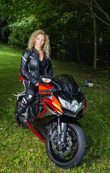 twenty something woman, wearing a leather jacket and pants, sitting on a sport motocycle