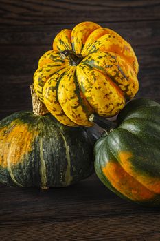 winter squash stack on top of the other against a dark wood background
