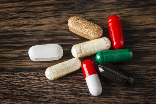 group of pills, tablets and capsule against a dark wood background