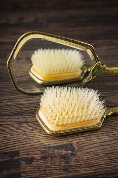 top part of a vintage mirror and hair brush against dark wood background
