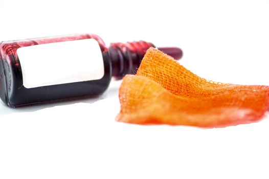 Studio macro of a pharmacy flask filled with a red liquid with a compress on a white background. Copy space.