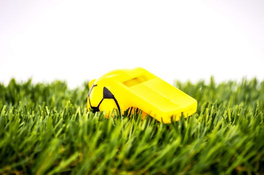 Yellow whistle soccer sports on grass background - penalty, foul or sport concept, selective focus