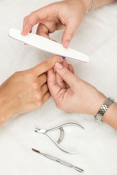 Woman in a nail salon receiving a manicure by a beautician with nail file. Nails manicure.