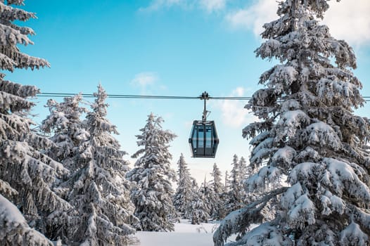 Sunshine over cable car to covered with snow during winter.