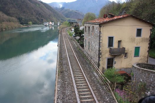 The Tuscan Serchio river in Borgo a Mozzano and the reflection of the sky on a cloudy day in medieval countryside