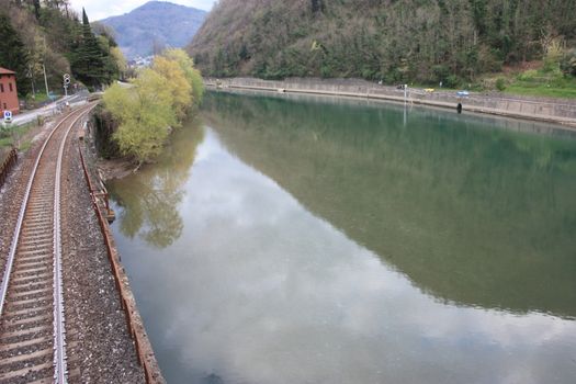 The Tuscan Serchio river in Borgo a Mozzano and the reflection of the sky on a cloudy day in medieval countryside