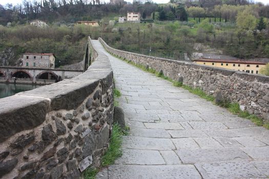 The suggestive and famous Ponte della Maddalena of Lucca built in bricks over a river in an ancient medieval village in Borgo a Mozzano