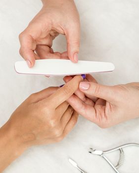 Woman in a nail salon receiving a manicure by a beautician with nail file. Nails manicure.