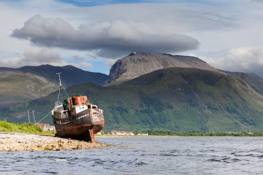The view across Loch Linnhe beyond an abandoned boat towards Ben Nevis, the highest mountain in Great Britain.