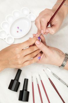 Master makes manicure to client using tool